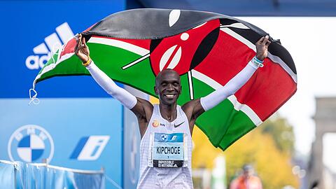 Eliud Kipchoge jubelt mit der kenianischen Flagge.