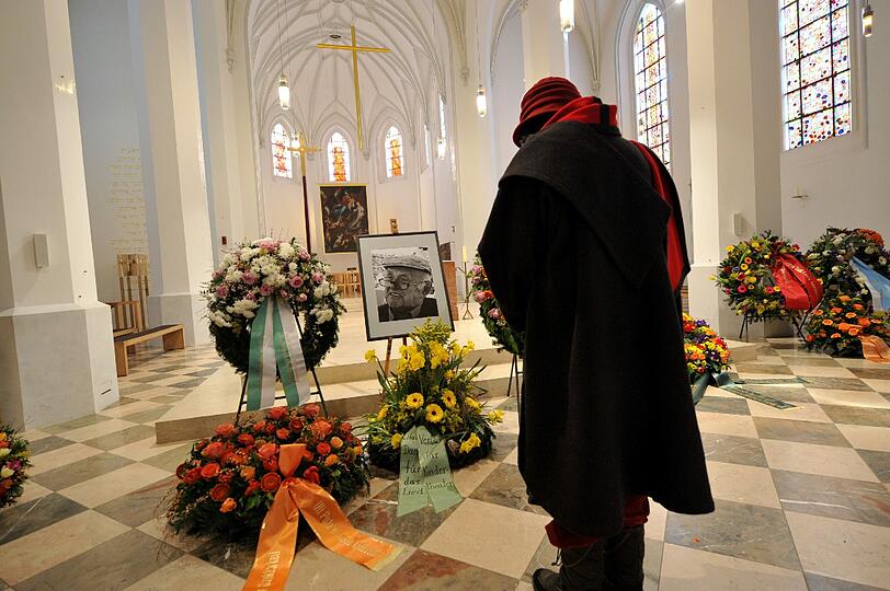 Vor dem Foto des Kinderbuchautors Otfried Preußler verneigt sich eine Frau vor Beginn der Trauerfeier