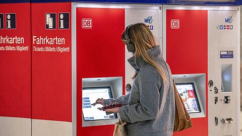 Eine Bahnkundin kauft in München an einem Fahrkartenautomaten ein Ticket - künftig soll das zu einem bundesweit einheitlichen Preis möglich sein. Doch einige Fragen sind offen.