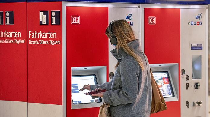 Eine Bahnkundin kauft in München an einem Fahrkartenautomaten ein Ticket - künftig soll das zu einem bundesweit einheitlichen Preis möglich sein. Doch einige Fragen sind offen.