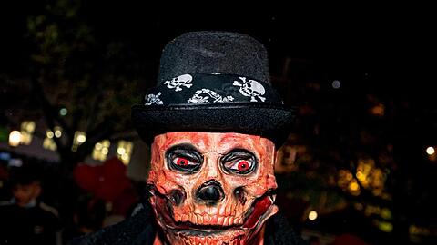Ein Mann mit einer Totenkopf-Maske und glühenden roten Augen bei der Essener Halloween-Parade. Neben fantasievollen Kostümen gab es in der Nacht in Teilen Deutschlands auch Ruhestörungen, Böllerwürfe und Ausschreitungen.