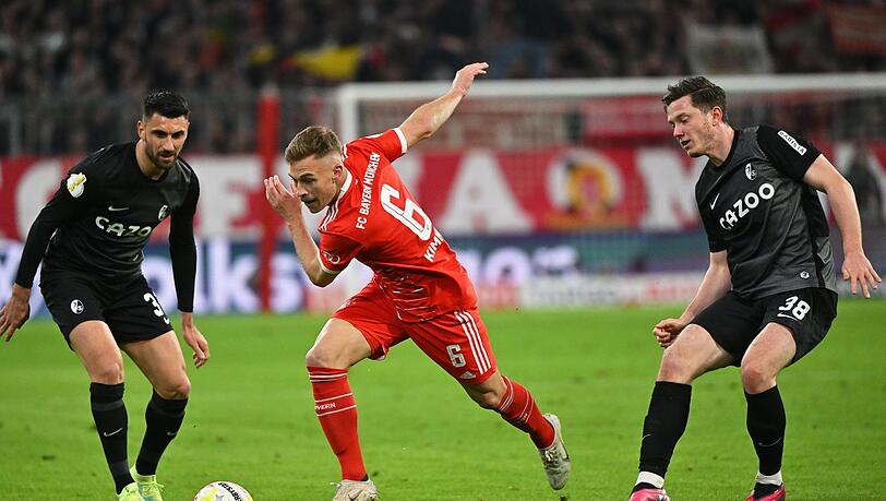 Joshua Kimmich (M) kämpft gegen Freiburgs Vincenzo Grifo (l) und Michael Gregoritsch um den Ball.