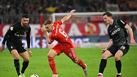 Joshua Kimmich (M) kämpft gegen Freiburgs Vincenzo Grifo (l) und Michael Gregoritsch um den Ball.