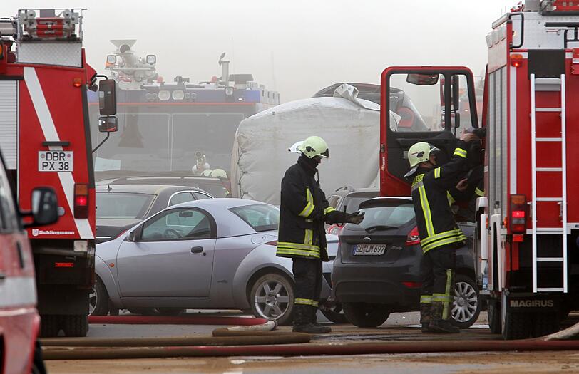 Feuerwehrleute sind am Freitag auf der Autobahn A19 bei Kavelstorf in der Nähe von Rostock bei einer Massenkarambolage im Einsatz. Bei einem Sandsturm fuhren in beiden Fahrtrichtungen Dutzende Fahrzeuge und LKW ineinander und brannten teilweise aus.