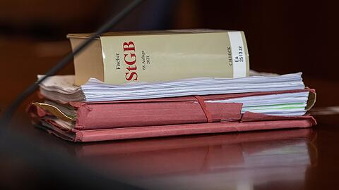 Das Strafgesetzbuch und Akten liegen in einem Gericht auf dem Tisch.
