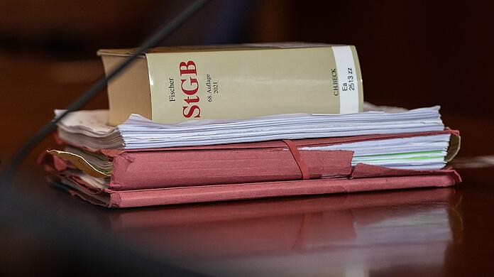 Das Strafgesetzbuch und Akten liegen in einem Gericht auf dem Tisch.