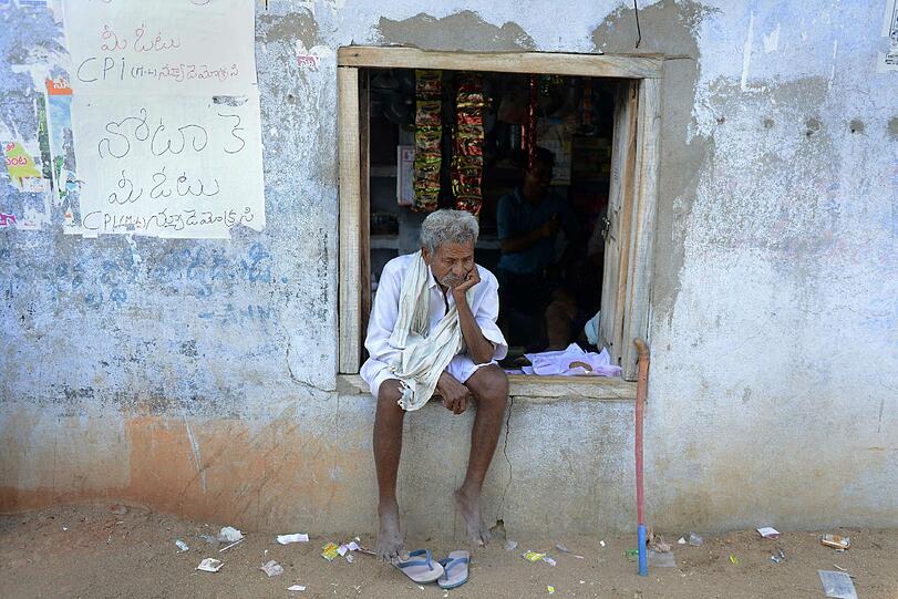 Ein Mann sitz in einem Fensterrahmen eines Wahllokals in Indien.