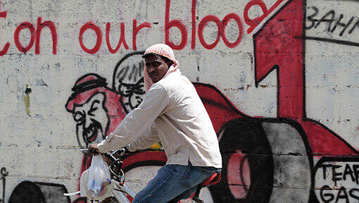 Ein Mann fährt auf dem Fahrrad an einem Graffiti vorbei, das Bilder von Bernie Ecclestone und dem König von Bahrain, Hamad bin Isa, zeigt. Ein Mann fährt auf dem Fahrrad an einem Graffiti vorbei, das Bilder von Bernie Ecclestone und dem König von Bahrain, Hamad bin Isa, zeigt.