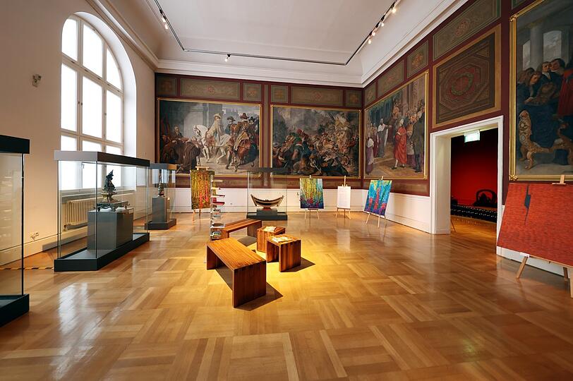 Kontrast: Alte Fresken mit Szenen aus der bayerischen Geschichte an der Wand, davor japanische Kunstwerke.