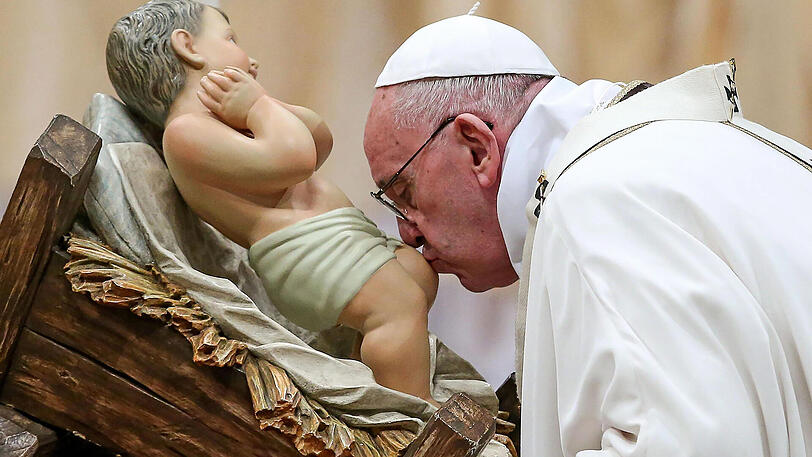 Papst Franziskus küsst während der Weihnachtsmesse am 24.12.2015 im Petersdom im Vatikan eine Figur, die den geborenen Jesus darstellt.