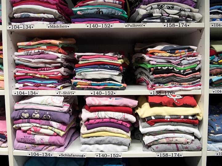 Kleidung liegt in den Regalen einer Kleiderkammer. Foto: Ralf Hirschberger/dpa-Zentralbild/dpa/Archivbild