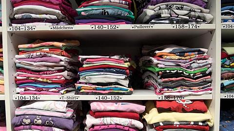 Kleidung liegt in den Regalen einer Kleiderkammer. Foto: Ralf Hirschberger/dpa-Zentralbild/dpa/Archivbild