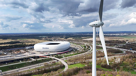 Eines der beiden Windräder der Stadtwerke München, im Hintergrund die Allianz Arena.