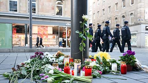 Kerzen und Blumen liegen in der Nähe des Paradeplatzes in Mannheim an einer Straßenbahnhaltestelle. (Archivfoto)