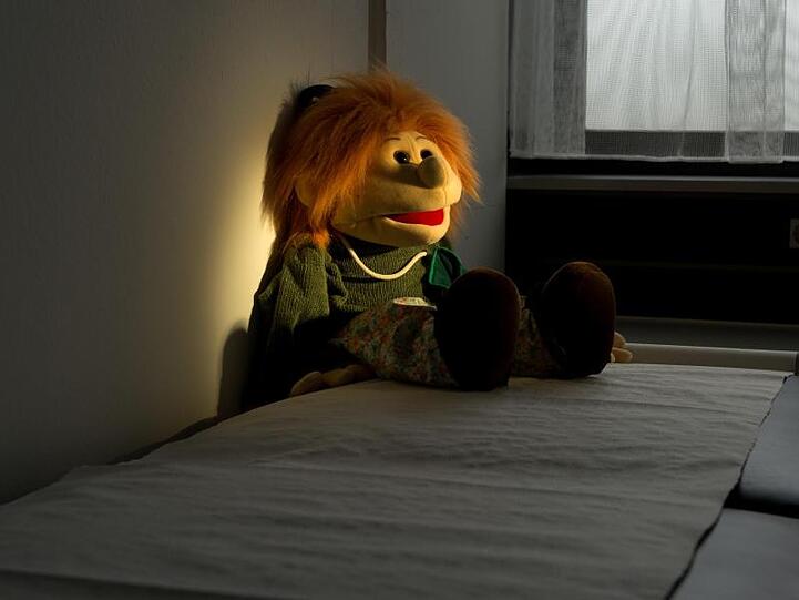 Eine Handpuppe sitzt auf einer Liege in einem Untersuchungsraum in der Kinderschutzambulanz. Foto: Julian Stratenschulte/dpa/Archivbild