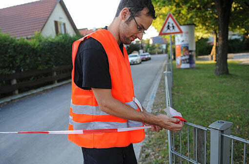 Vorbereitung für die Entschärfung oder Sprengung der Bombe: Ein Mann bringt ein Absperrband an.