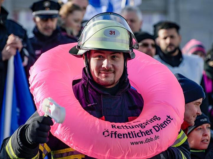 Ein Feuerwehrmann steht mit einem Rettungsring um den Hals an der Hamburger Binnenalster.