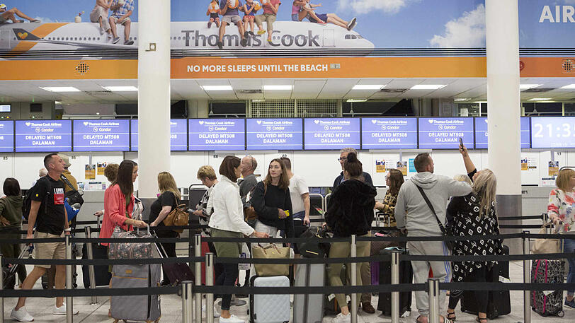 Urlauber stehen an einem Check-In-Schalter von Thomas Cook im Südterminal des Flughafens Gatwick.