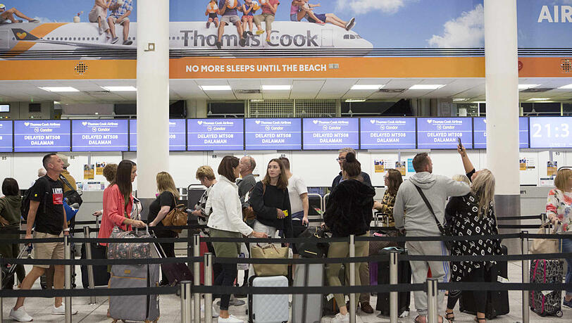 Urlauber stehen an einem Check-In-Schalter von Thomas Cook im Südterminal des Flughafens Gatwick.