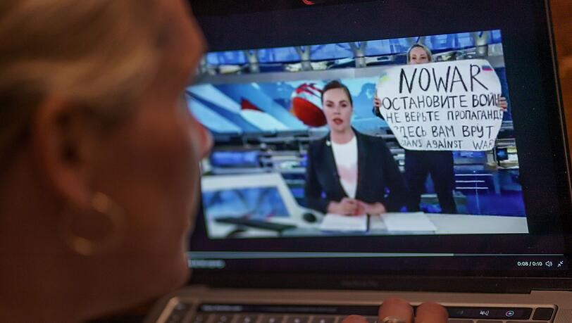 Mit einem Protestplakat und lauten Rufen hatte eine Kriegsgegnerin im russischen Staatsfernsehen für eine Unterbrechung der Hauptnachrichtensendung gesorgt.