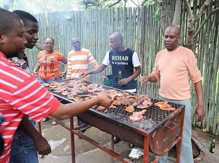 Männer grillen Fleisch für eine traditionelle afrikanische Mahlzeit vor dem Bakone Malapa Museum bei Polokwane (Südafrika).