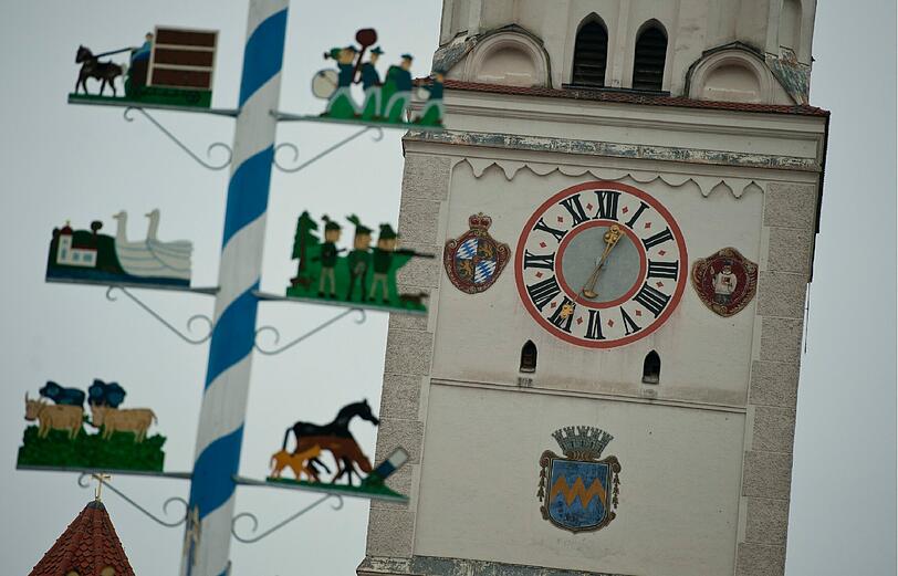 Die Figuren eines Maibaums vor dem Turm der Pfaffenhofener Stadtpfarrkirche Sankt Johannes Baptist.