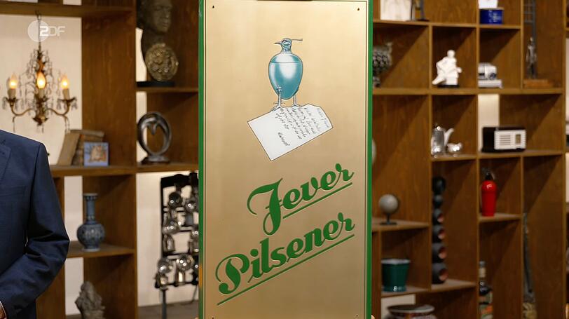 Das Werbeschild war von Jever Pilsener, das seit 1848 in der friesischen Stadt Jever gebraut wurde. Lichter fiel jedoch vor allem das ungewöhnliche Motiv ins Auge: Zu sehen war ein Kiebitz-Becher, der einst als Markenzeichen der Brauerei diente und eng mit der Geschichte der Stadt Jever verbunden war. Das Werbeschild war von Jever Pilsener, das seit 1848 in der friesischen Stadt Jever gebraut wurde. Lichter fiel jedoch vor allem das ungewöhnliche Motiv ins Auge: Zu sehen war ein Kiebitz-Becher, der einst als Markenzeichen der Brauerei diente und eng mit der Geschichte der Stadt Jever verbunden war.