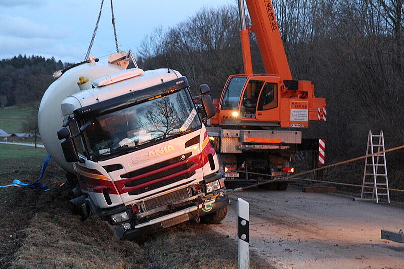 Ein Bergungsfahrzeug und zwei Kräne werden benötigt um den vollbeladenen LKW wieder auf die Straße zu ziehen.