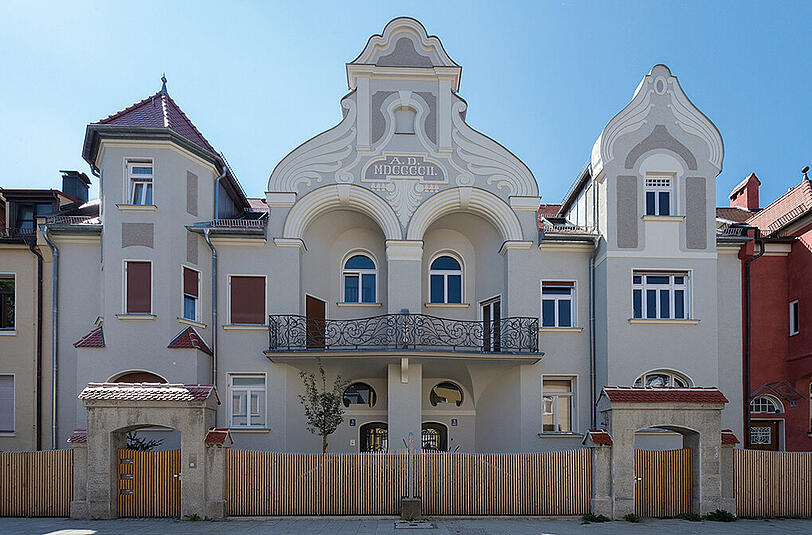 Wilhelm-Düll-Straße 3/5: Die beiden Häuser mit gemeinsamen Jugendstil-Eisenbalkon sind 1902 von Rudolf Hofmann als Teil einer Reihenhausgruppe in der Villenkolonie Gern im historisierenden Stil errichtet worden.