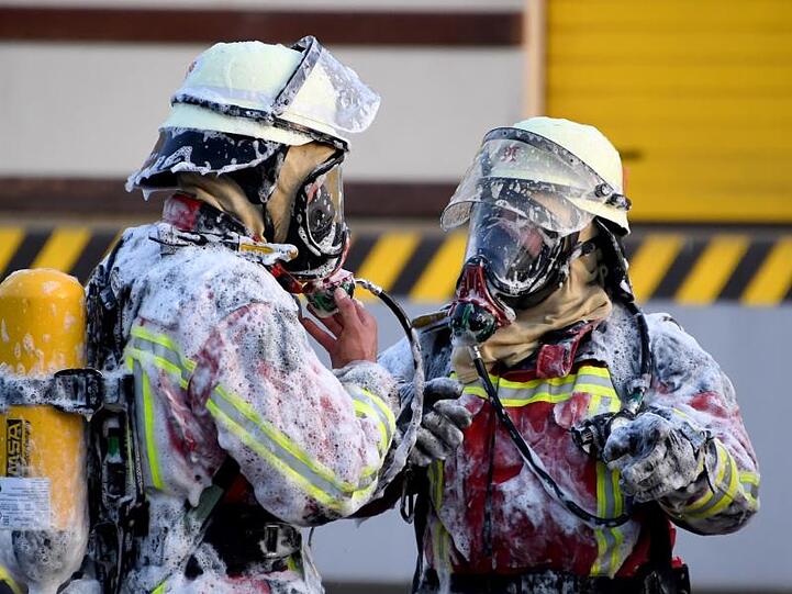 Mit Löschschaum beschmutzte Feuerwehrmänner stehen bei einem Einsatz. Foto: Carsten Rehder/Archivbild