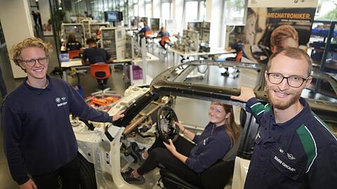 Ausbilder Andreas Mauer (r.) mit Lukas Röwe (l.) und Julia Deppe (im Auto), die sich beide im Dualen Studium im Bereich System- und Hochvolttechnik bei BMW befinden.