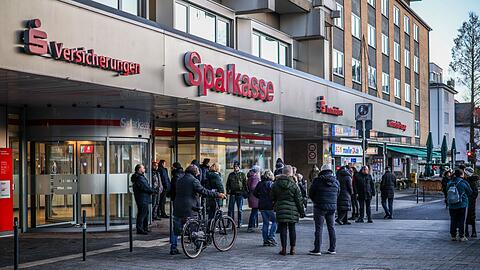 Nach einem Einbruch in den Tresorraum einer Bankfiliale in Gelsenkirchen warten Menschen vor dem Eingang auf Informationen.