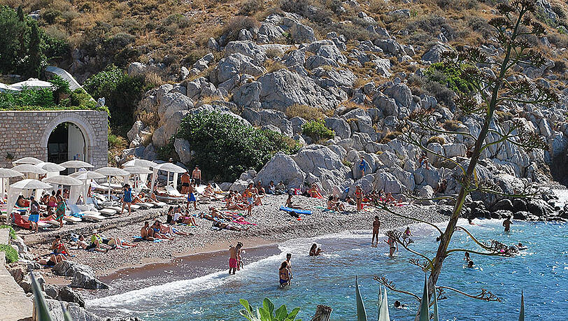 Urlauber und Sonnenhungrige tummeln sich an einem Strand auf der Ferieninsel Hydra (Griechenland). Urlauber und Sonnenhungrige tummeln sich an einem Strand auf der Ferieninsel Hydra (Griechenland).