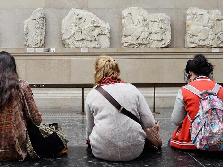 Besucher des British Museum in London sitzen vor Parthenon-Friesteilen.