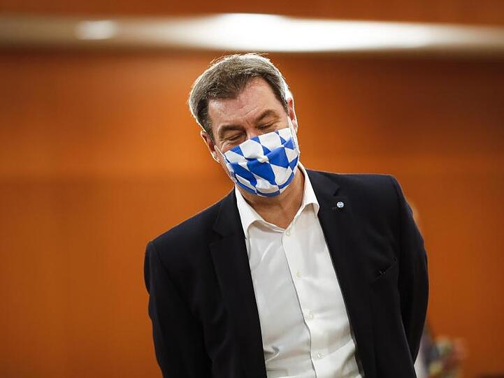 Markus Söder, Ministerpräsident von Bayern, trägt eine Gesichtsmaske mit dem weiß-blauen Rautenmuster Bayerns. Foto: Markus Schreiber/AP-Pool/dpa/Archivbild