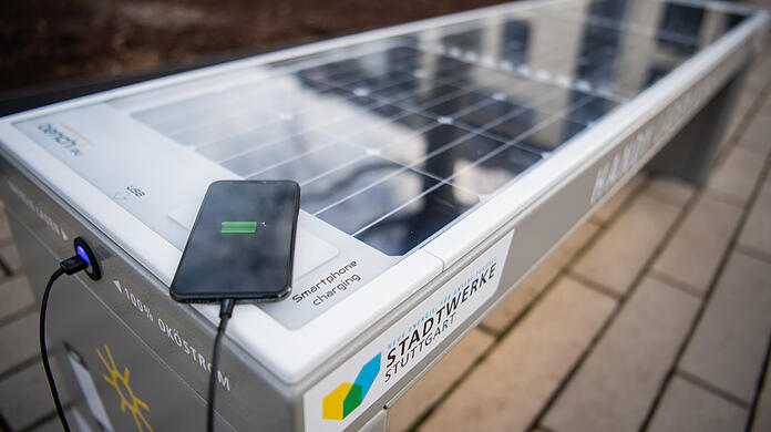 Eine Mobiltelefon liegt auf einer Solar-Sitzbank welche auf dem Marktplatz im Stadtteil Botnang steht. Solarzellen in der Sitzfläche versorgen bis zu vier Mobiltelefone gleichzeitig mit Ökostrom sowie mit kostenfreiem WLAN. +++ dpa-Bildfunk +++