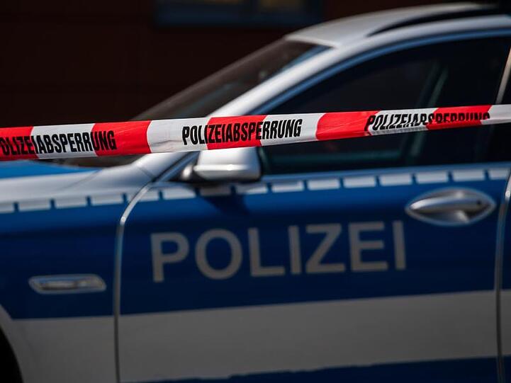 Ein Polizeiauto steht hinter einem Absperrband der Polizei.