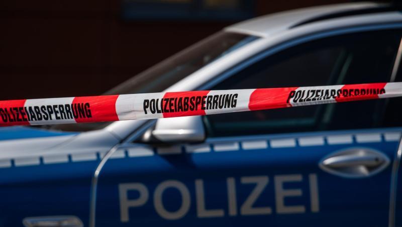 Ein Polizeiauto steht hinter einem Absperrband der Polizei. Ein Polizeiauto steht hinter einem Absperrband der Polizei.