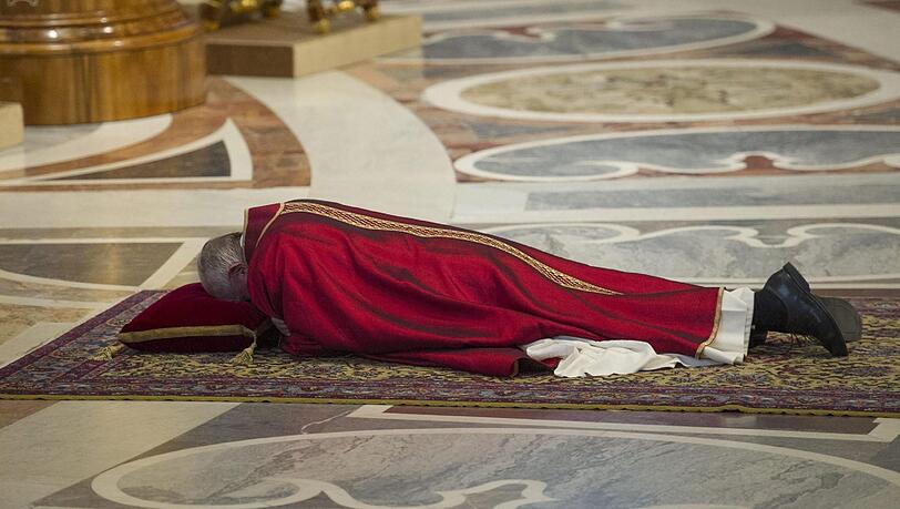 Papst Franziskus betet auf dem Boden liegend. Papst Franziskus betet auf dem Boden liegend.