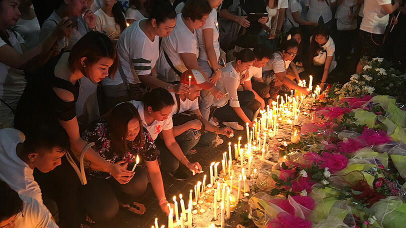 Trauernde legen in Manila Kerzen und Blumen vor dem Resort World Manila Entertainment Gebäude nieder.
