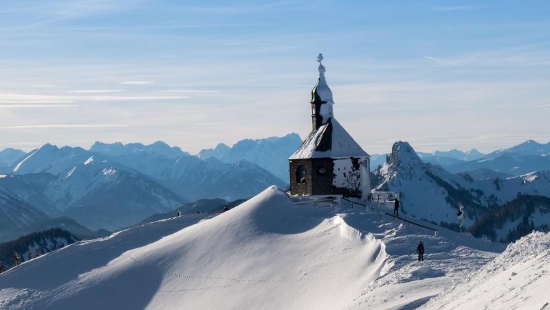 Skifahrer laufen zur Piste unterhalb der vom Schnee bedeckte Wallberg-Kapelle "Heilig Kreuz". Foto: Peter Kneffel Skifahrer laufen zur Piste unterhalb der vom Schnee bedeckte Wallberg-Kapelle "Heilig Kreuz". Foto: Peter Kneffel