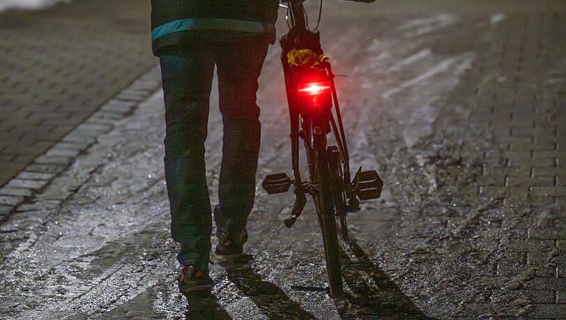 Ein Mann schiebt sein Fahrrad auf einer vereisten Stra&szlig;e.