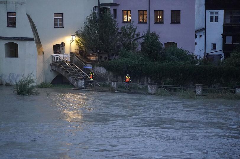 Feuerwehrleute sind am Ufer in Wasserburg auf Kontrollgang.