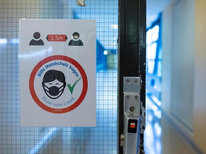 Ein Schild mit der Aufschrift "Bitte Mundschutz tragen" ist in einem Flur zu sehen. Foto: Sven Hoppe/dpa
