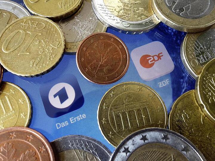 Euromünzen liegen neben den Logos der Apps von ARD und ZDF.