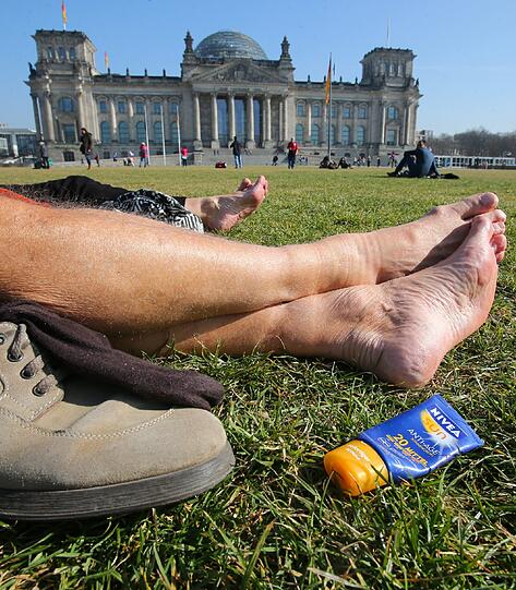 Touristen aus München genießen den Sonnenschein vor dem Reichstagsgebäude in Berlin