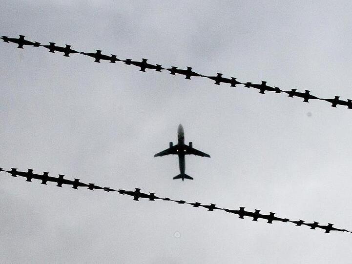 Ein Flugzeug ist hinter Stacheldraht zu sehen. Foto: Julian Stratenschulte/Archiv