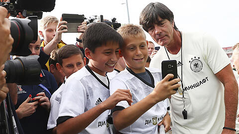 Bundestrainer Joachim Löw gibt auf dem Trainingsgelände in Sotschi Autogramme und posiert bei Selfies jugendlicher Fans.