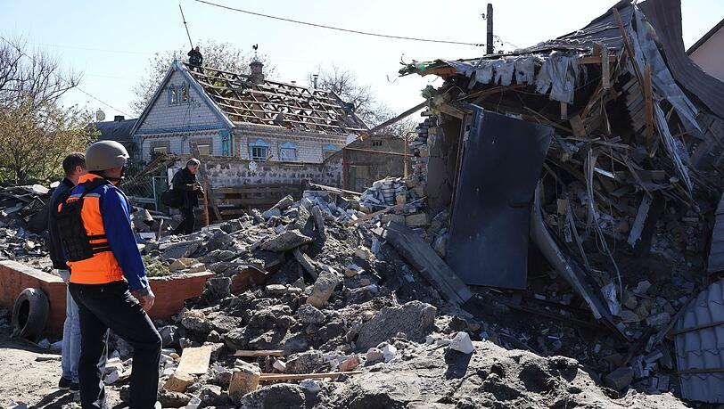Menschen betrachten ein Gebäude in Saporischschja, dass nach ukrainischen Angaben durch russischen Beschuss zerstört wurde.