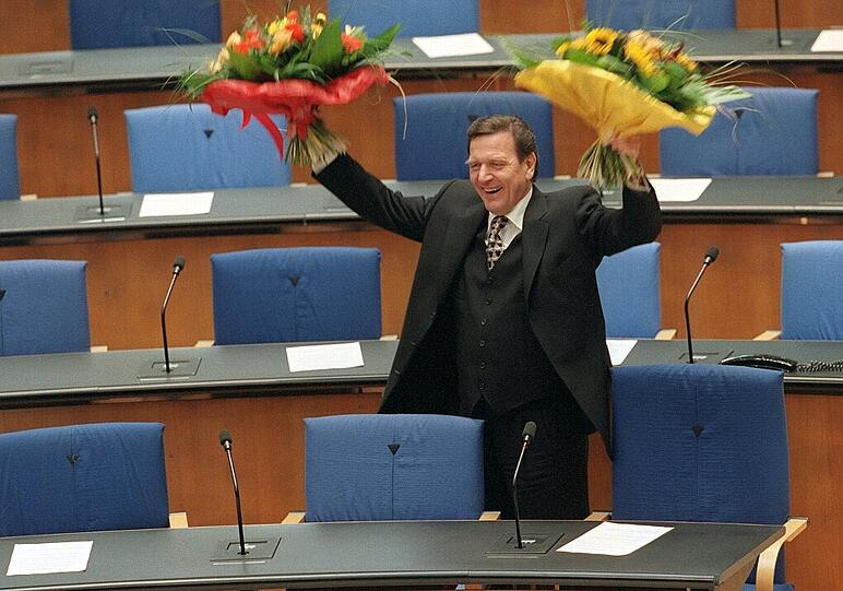 Wink mit Blumen: Bundeskanzler Gerhard Schröder steht am 27. Oktober 1998 im Bundestag von Bonn neben seinem Platz in der Regierungsbank. Gerade hat er seinen Amtseid abgelegt.